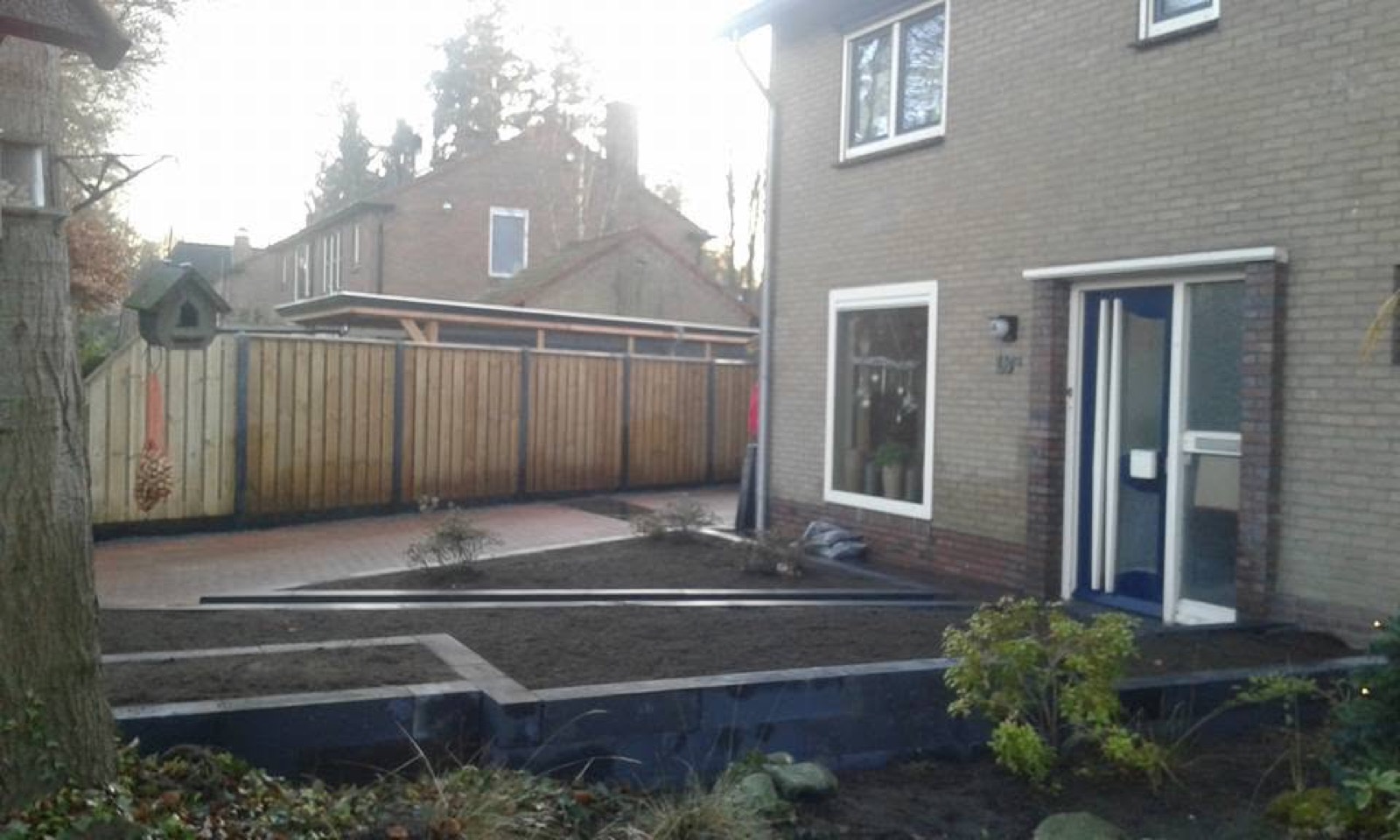 Tuin met hoogteverschil, schutting, borders en terras